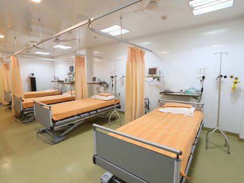 Four outpatient beds behind curtain rails at Jananam Fertility Centre, Neelankarai, with monitors, oxygen points and drip stands