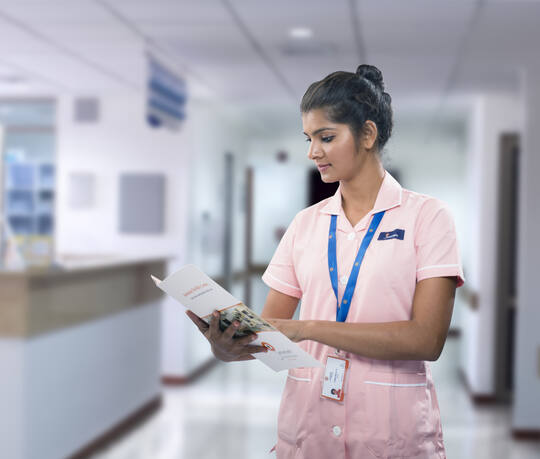 A Jananam nurse on duty in the corridor at the Neelankarai hospital, Chennai, reading a patient file